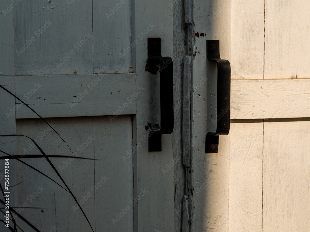 An old white wooden door with a simple bent iron handle