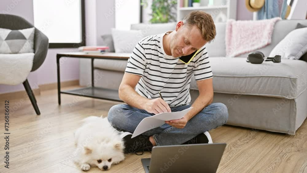 Chilled out young caucasian man deep in a lively chat on his smartphone, scribbling notes while his faithful pet dog lounges nearby, all from the comfort of his cozy living room. Chilled out young caucasian man deep in a lively chat on his smartphone, scribbling notes while his faithful pet dog lounges nearby, all from the comfort of his cozy living room.
