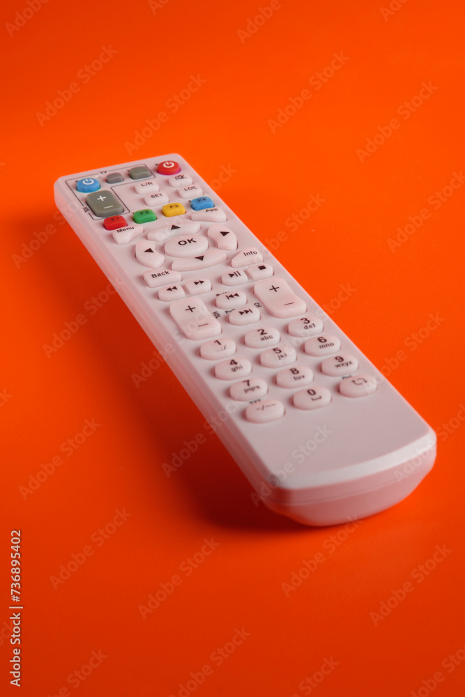 a TV remote with various function buttons on a lit background a TV remote with various function buttons on a lit background