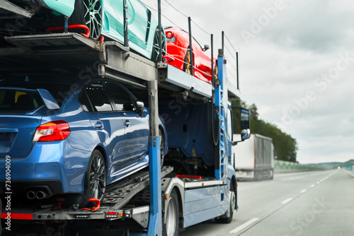 Car carrier trailer truck with brand new exotic luxury sport cars for a racing championship  car show or sale. Car transporter trailer loaded with italian car. Two-level modular hydraulic semi-trailer