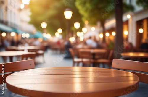 Empty wooden table and blurred background of city restaurant, coffee shop for display of montage product. Bokeh effect. Scene round wood tabletop counter on blur cafe, bar. Banner. Outdoors, outside.