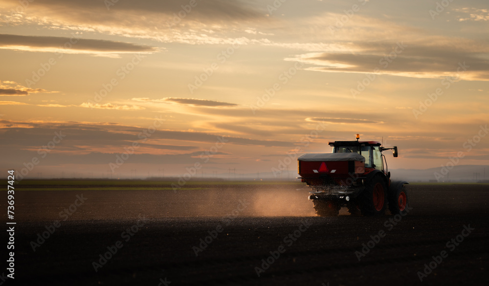 Fototapeta premium Tractor spreading artificial fertilizers in field