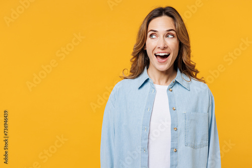 Young shocked exultant fun surprised excited woman she wear blue shirt white t-shirt casual clothes look aside on workspace area isolated on plain yellow background studio portrait. Lifestyle concept. photo