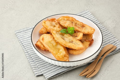 Pisang Goreng Wijen or banana fritters with sesame seed served in white plate. Indonesian food
