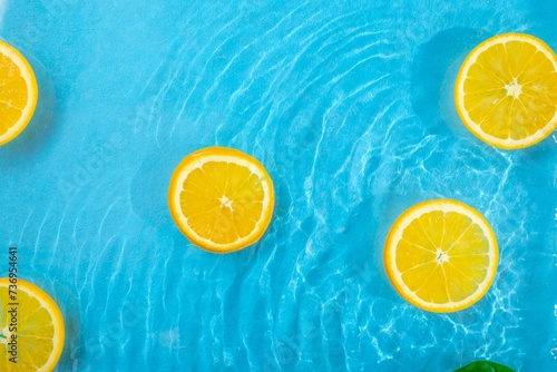 Fresh juicy orange slices and leaf floating in the water. Healthy food and beverages concept. Pastel colors pattern. Natural citrus fruit background. Minimal flat lay. Organic agriculture idea.