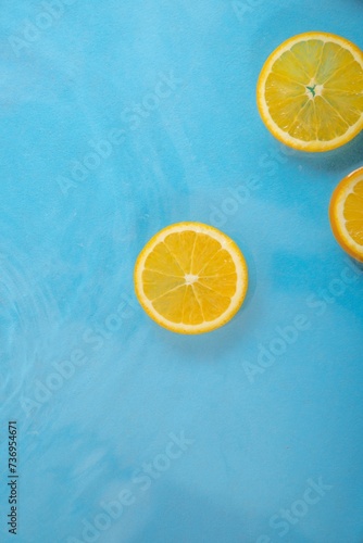 Fresh juicy orange slices and leaf floating in the water. Healthy food and beverage concepts. Pastel colors pattern. Natural citrus fruit background. Minimal flat lay. Organic agriculture idea.