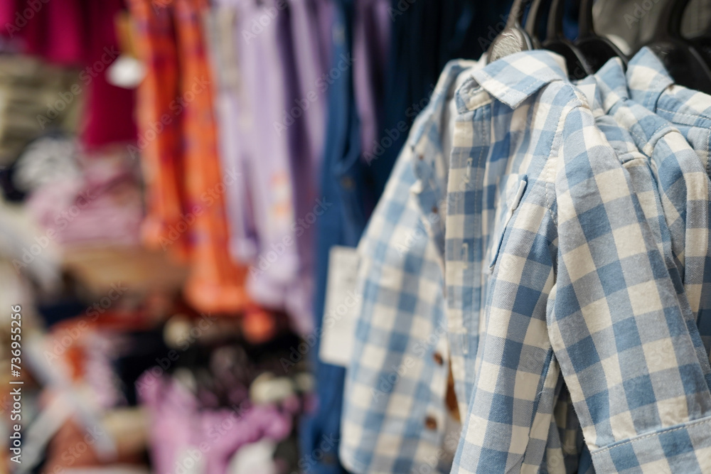 Fototapeta premium Children clothes hanging on hangers in the shop