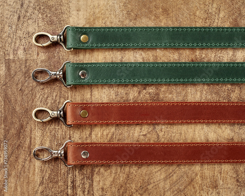 Collection of leather bag straps with carabiners on wooden surface