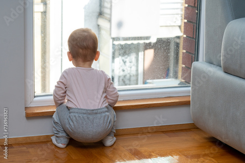 Toddler by the window, waiting for daddy. Concept of patience and familial love