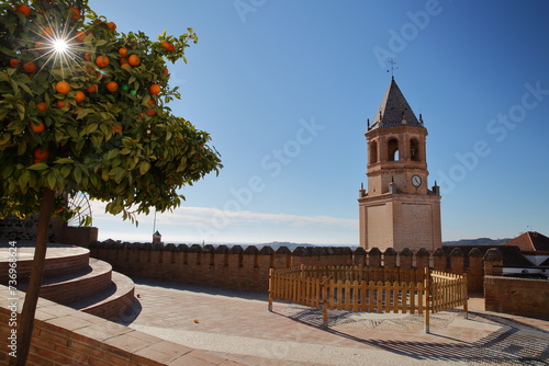 The impressive bell tower of the church of San Juan Bautista in Velez Malaga, Malaga province, Andalusia, Spain, with ramparts in the foreground