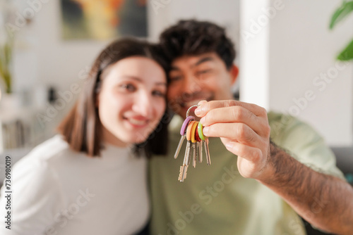 Ecstatic young couple smiling and holding up a set of new house keys, marking a joyous occasion photo