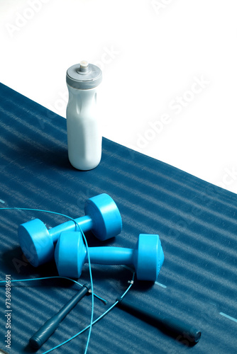 Set for practicing exercise with dumbbells and skipping rope on a mat