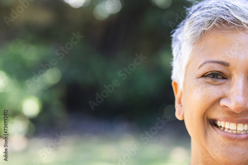 A mature biracial woman smiling enjoys a sunny day outdoors with copy space photo