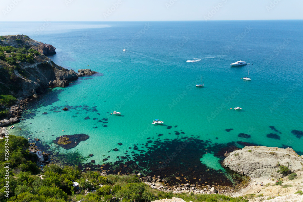 Pleasure boats in a beautiful sea lagoon. View from the top of the cliff. Azure-emerald green sea water on a sunny day.