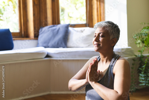 A mature biracial woman practices yoga at home, with copy space photo