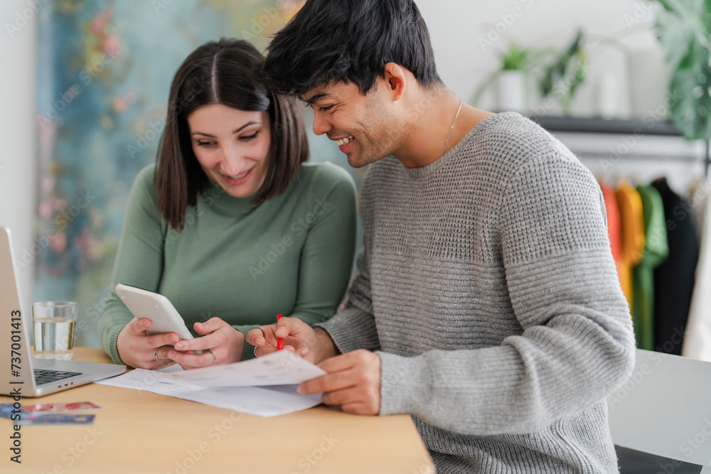 Couple collaborating on financial paperwork with laptop and credit cards on table Couple collaborating on financial paperwork with laptop and credit cards on table