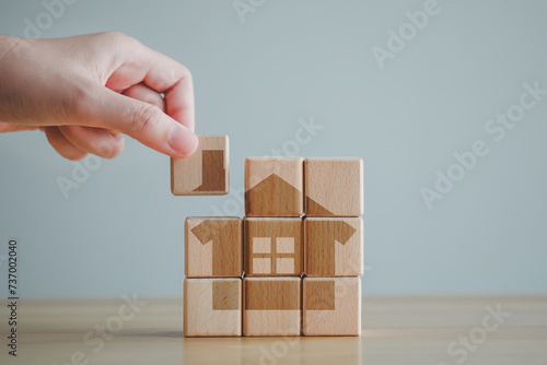 Real estate, Property investment and asset management, Housing finance and home loan concept. Hand puting part of house into wooden blocks refer to start a family or buy or rent home.