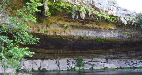 Static video of a rock wall and cave entrance at the Hamilton Pool Preserve in Wimberly Texas.  Cliff Swallows and nest can be seen under the rock ledge. photo