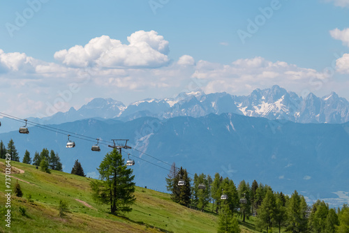 Ski lift in summer with scenic view of majestic mountain range Julian Alps seen from Gerlitzen, Carinthia, Austria. Wanderlust in Austrian Alps. Idyllic hiking trail along alpine meadow and forest photo