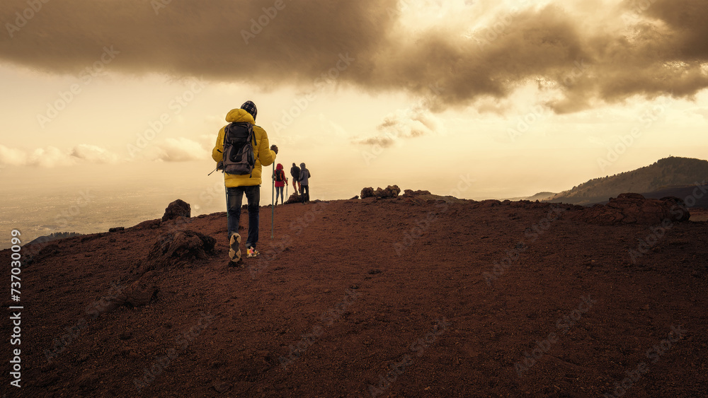 Hikers trekking across the volcanic terrain of Mount Etna - Adventure and exploration in the dramatic Sicilian landscape.