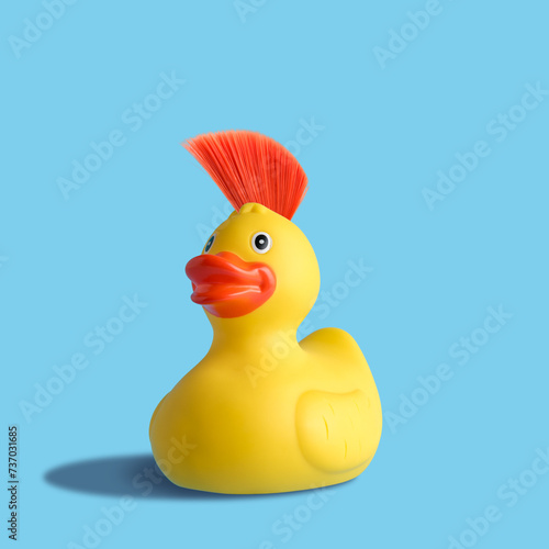 Yellow rubber duck with mohawk on blue background. Summer minimal concept. photo