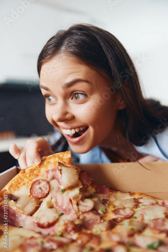 Woman admiring delicious pizza with cheese and meat in open box on table