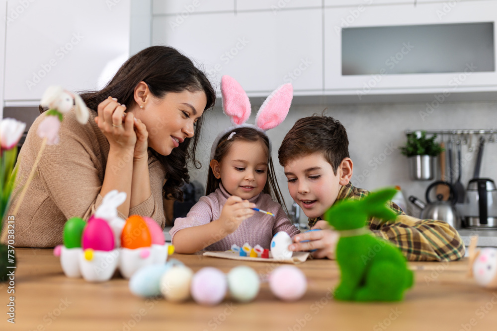 Easter, family, holiday and child concept - close up of little girl, boy and mother coloring eggs for easter. Happy Family Painting Easter Eggs On Kitchen Table. Easter, family, holiday and child concept - close up of little girl, boy and mother coloring eggs for easter. Happy Family Painting Easter Eggs On Kitchen Table.