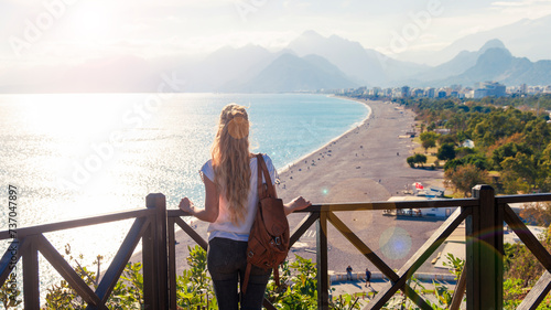Woman tourist enjoying panoramic view of beach of Antalya with mountain and sunlight- turkey