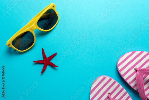 Creative composition with seashells, sunglasses and beach slippers on blue background. Summer minimal concept.