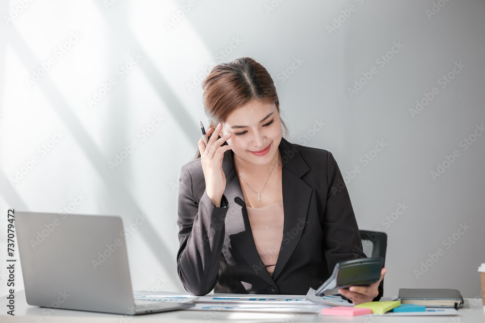 Asian Business woman using calculator and laptop for doing math finance on an office desk, tax, report, accounting, statistics, and analytical research concept Asian Business woman using calculator and laptop for doing math finance on an office desk, tax, report, accounting, statistics, and analytical research concept