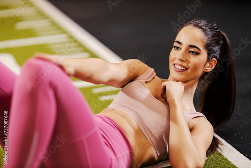 A fit sportswoman is doing crunches in a gym.
