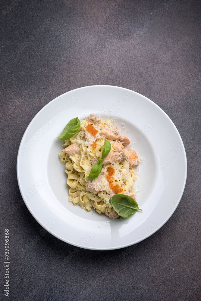 Pasta with salmon, cream sauce and basil on a white plate