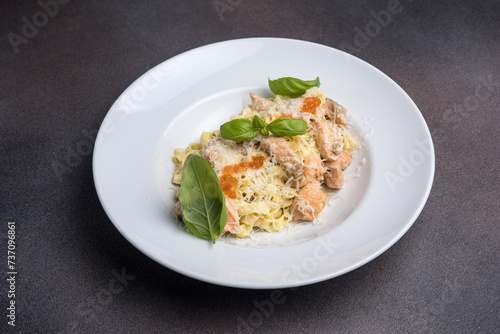 Pasta with salmon, cream sauce and basil on a white plate