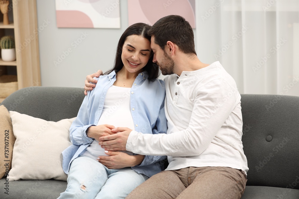 Happy pregnant woman with her husband on sofa at home Happy pregnant woman with her husband on sofa at home