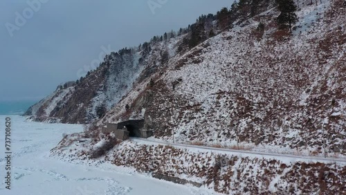 Aerial drone view tunnels and bridges winter circum-Baikal railway at the foot of the mountains on the coast of Lake Baikal, Siberia, Russia. High quality 4k footage