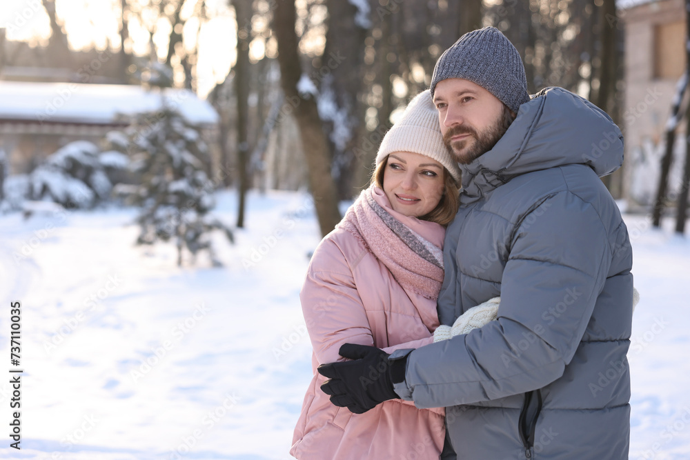 Family portrait of beautiful couple in snowy park. Space for text Family portrait of beautiful couple in snowy park. Space for text