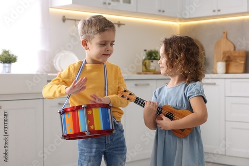 Little children playing toy musical instruments in kitchen photo