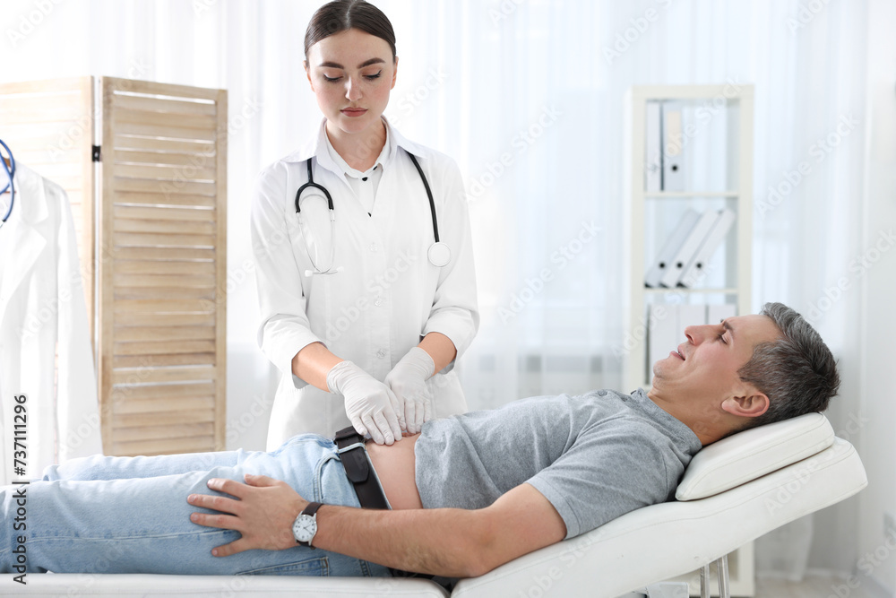 Gastroenterologist examining patient with stomach pain on couch in clinic Gastroenterologist examining patient with stomach pain on couch in clinic