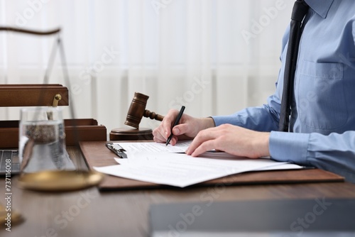 Lawyer working with documents at wooden table indoors, closeup