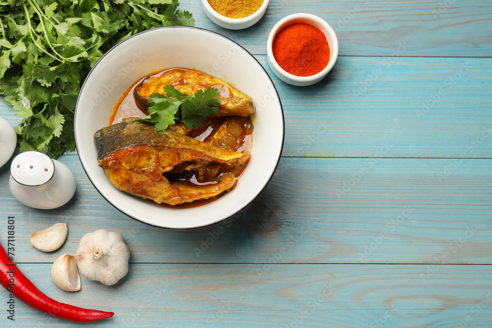 Tasty fish curry and ingredients on light blue wooden table, flat lay. Space for text. Indian cuisine Tasty fish curry and ingredients on light blue wooden table, flat lay. Space for text. Indian cuisine