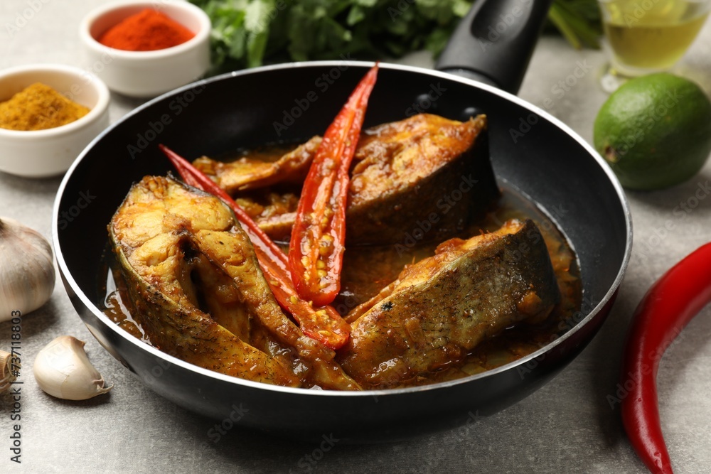 Tasty fish curry in frying pan and ingredients on light grey table, closeup. Indian cuisine - obrazy, fototapety, plakaty 