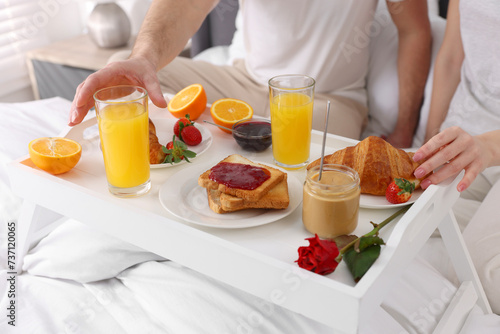 Couple eating tasty breakfast on bed, closeup