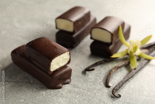 Glazed curd cheese bars, vanilla pods and flower on grey table, closeup