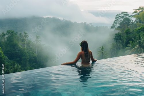 Tranquil Retreat: Young Woman Swimming in Resort Pool Overlooking Lush Mountain Vistas photo