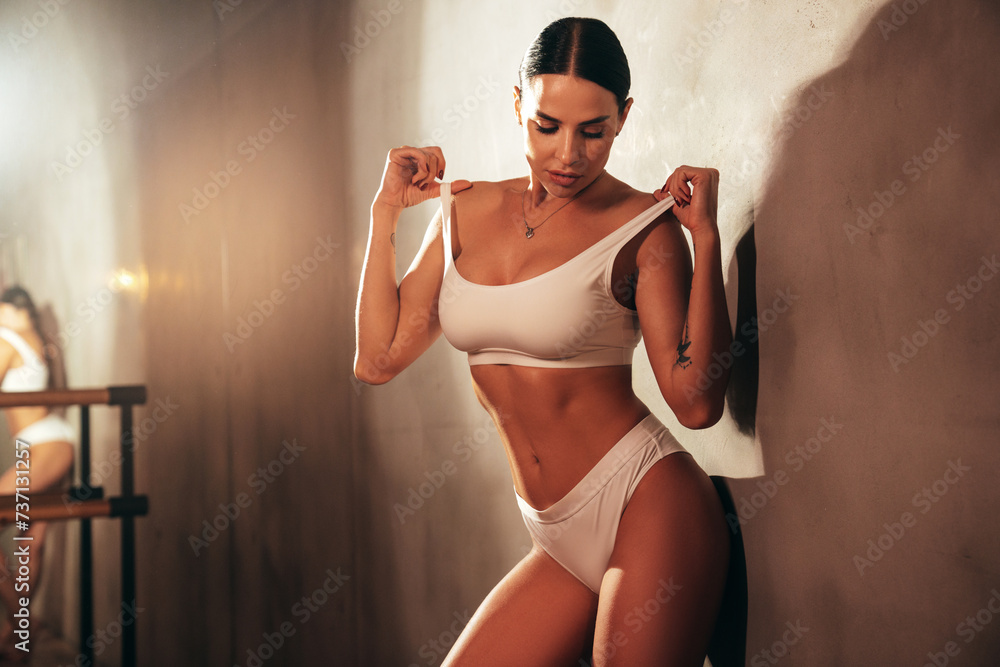 High fashion portrait of young beautiful sexy woman. Carefree model wearing pure white lingerie with big breasts. Hot tanned female posing in interior in studio in summer swimwear bathing suit - obrazy, fototapety, plakaty 