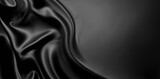 A black and white image of a wave of black silk. The silk has a wavy texture and appears to be in motion. The background is a gradient of black to white