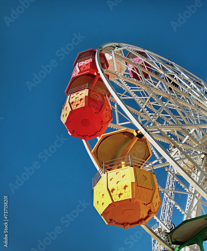 Ferris wheel with colorful booths against a blue sky