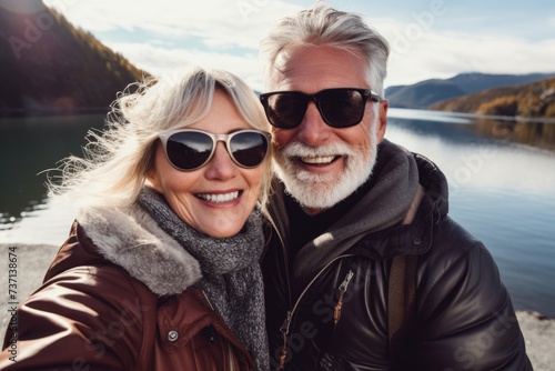 A couple of pensioners in sunglasses take selfies on a smartphone while traveling in the mountains © Evon J