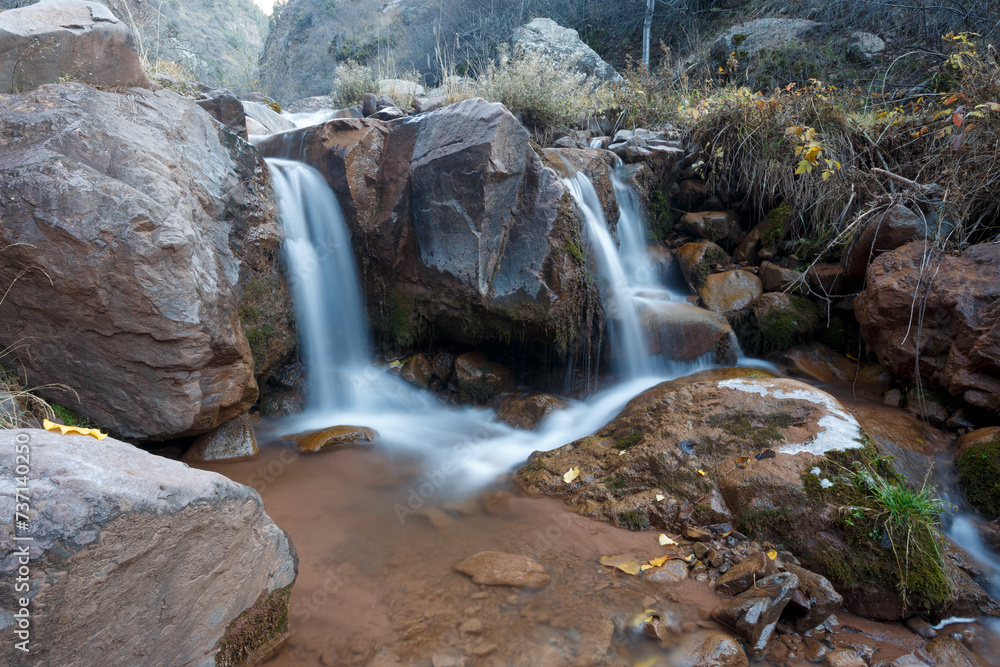 Waterfall in the mountains. Long exposure of a small waterfall flowing over rocks in Ala Archa National Park, Kyrgyzstan. Waterfall in the mountains. Long exposure of a small waterfall flowing over rocks in Ala Archa National Park, Kyrgyzstan.