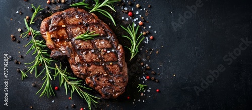 A delicious grilled steak seasoned with rosemary and pepper, served on a black surface. The perfect combination of flavors from natural ingredients like herbs and spices